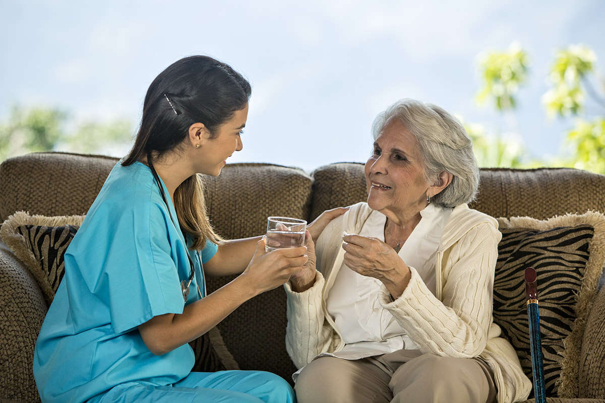 Nurse providing liquid to resident taking medicaiton